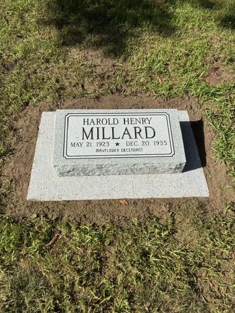 A real flat granite memorial set in a pale foundation with a neatly edged border