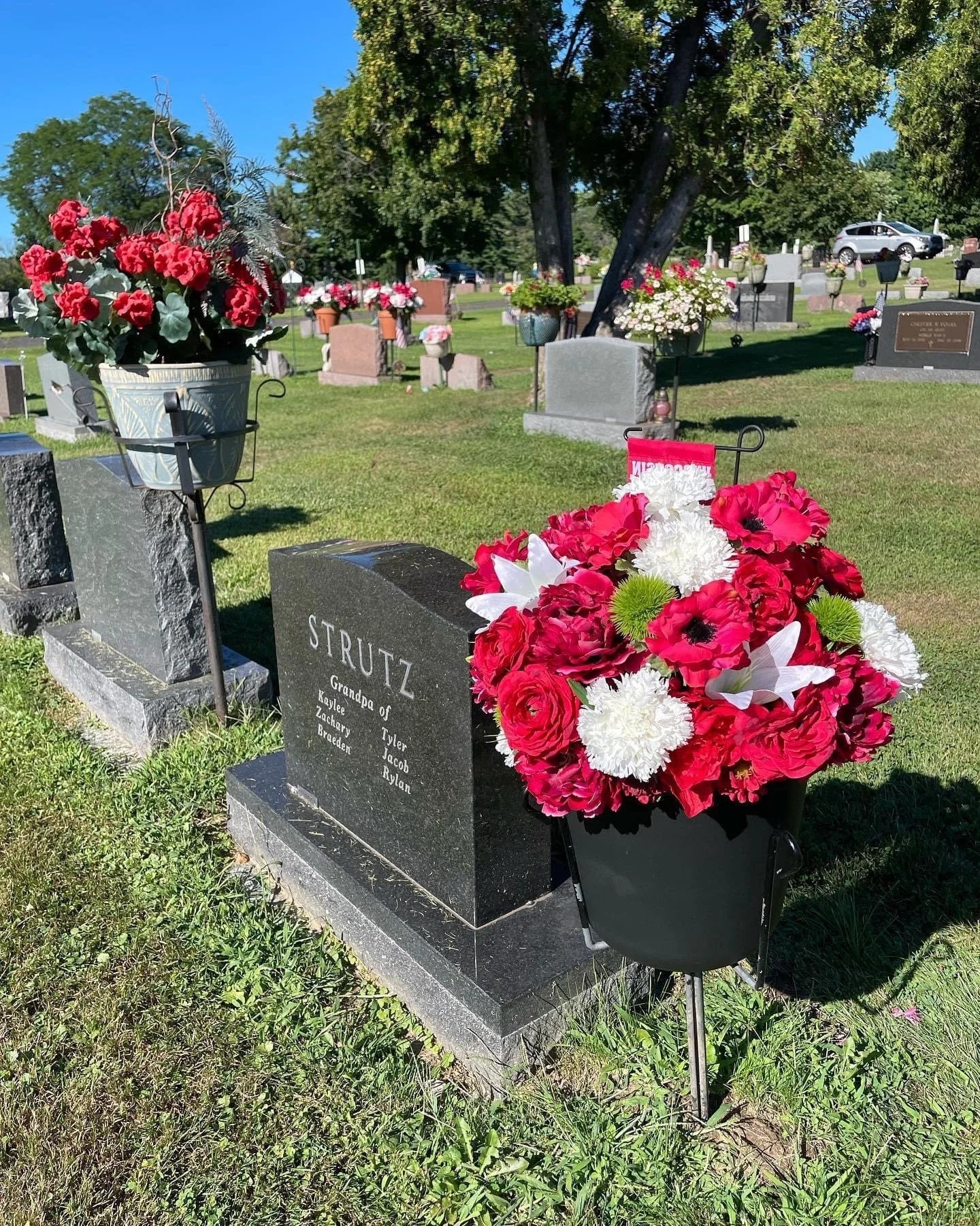 A real red and white custom floral wreath with a Wisconsin Badgers emblem at a memorial